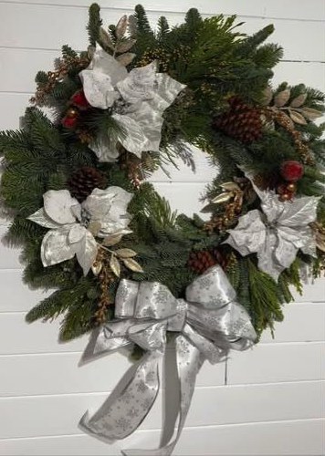 A fresh evergreen wreath with pinecones and a silver ribbon